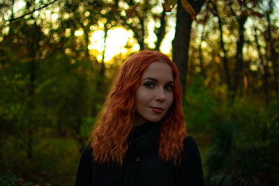 Portrait of young woman standing against trees