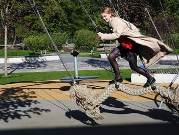 Girl seesawing against trees