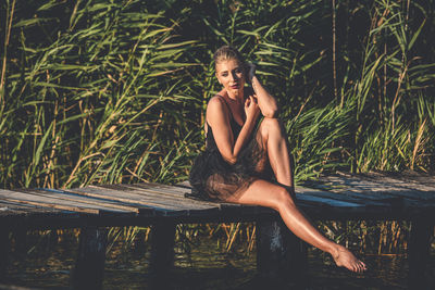 Full length of woman sitting on wood