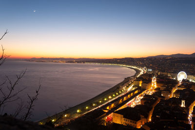 Aerial view of illuminated city against sky at sunset