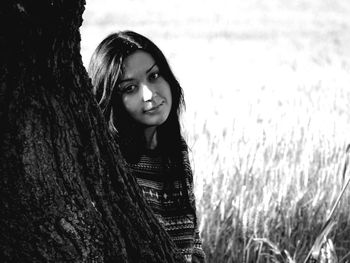 Portrait of young woman against tree trunk