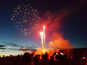 People looking at firework display during night