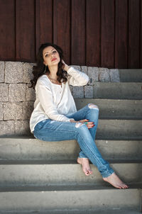 Portrait of woman sitting on staircase against wall