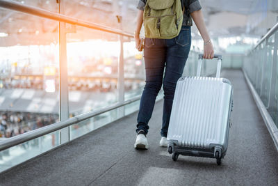 Low section of woman walking with luggage at airport