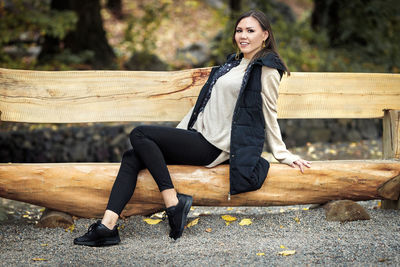 Portrait of young woman sitting on wooden bench