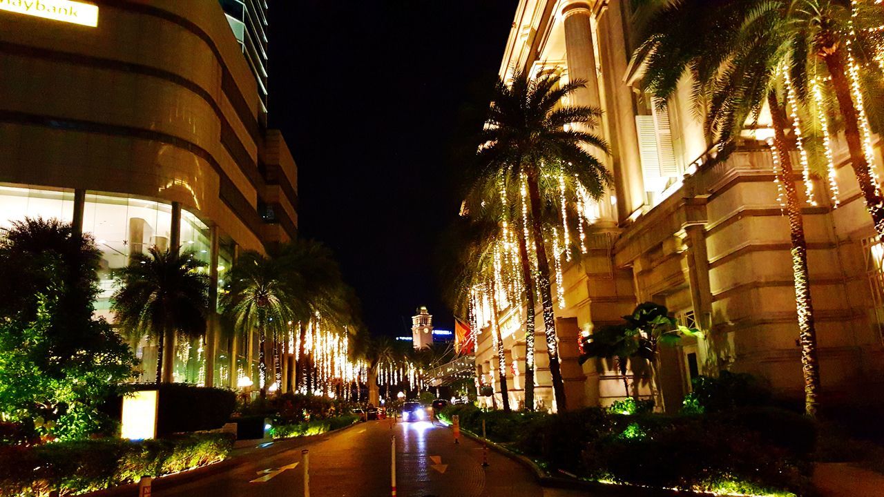 ILLUMINATED ROAD AMIDST BUILDINGS IN CITY AT NIGHT