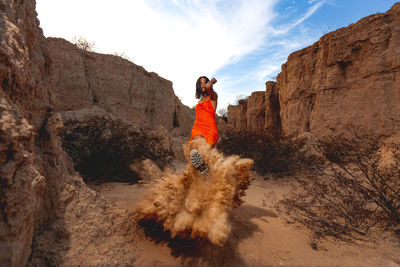 Woman standing on rock against sky