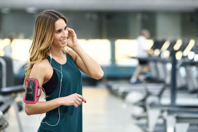Woman listening music while standing in gym