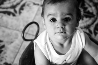 High angle portrait of cute baby boy sitting on floor at home