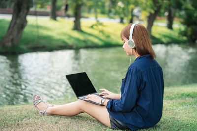 Young woman using laptop while sitting in park