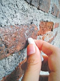 Close-up of hand holding stone wall