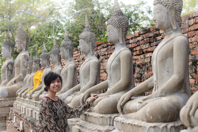 Portrait of woman standing by buddha statues