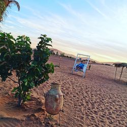 Deck chairs on beach against sky during sunset