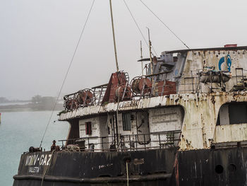 Abandoned ship moored in sea against clear sky