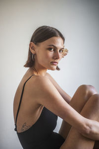 Portrait of young woman standing against white background