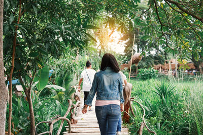 Rear view of people walking on plants