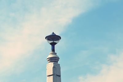 Low angle view of street light by building against sky