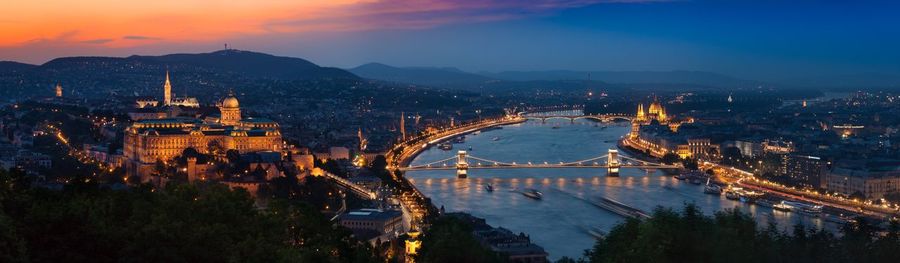 Panoramic image of illuminated buildings in city during sunset