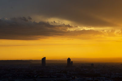 Silhouette buildings in city during sunset