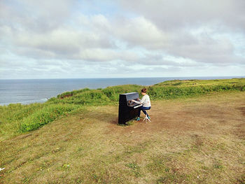 Man sitting on land against sky