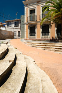 Footpath by palm trees and buildings in city