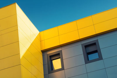 Low angle view of a yellow  building against blue sky.