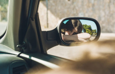 Reflection of man in side-view mirror