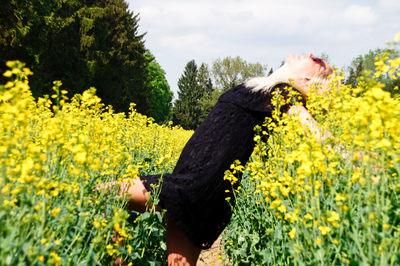 Young woman amidst yellow flowers on oilseed rape field