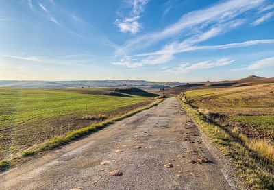 Road amidst field against sky