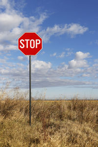 Information sign on field against sky