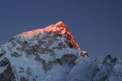 Low angle view of snowcapped mountain against clear sky