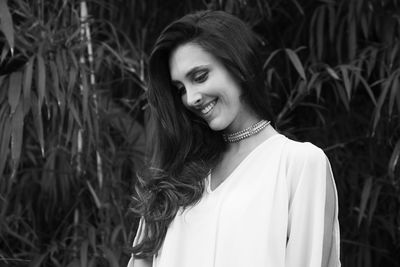 Smiling young woman standing against trees