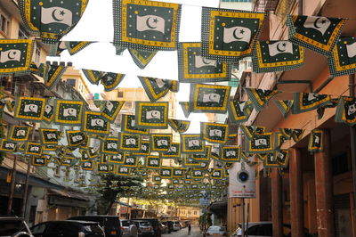 Low angle view of decorations hanging on street amidst buildings in city
