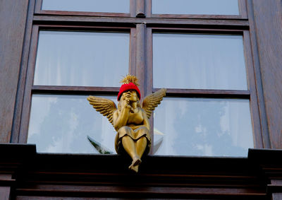 Low angle view of statue against window of building