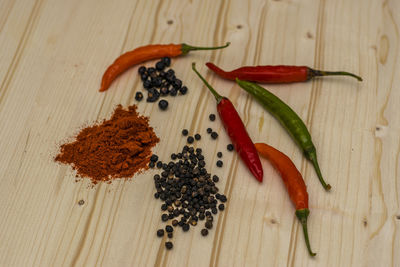 Close-up of red chili peppers and black peppercorn on table