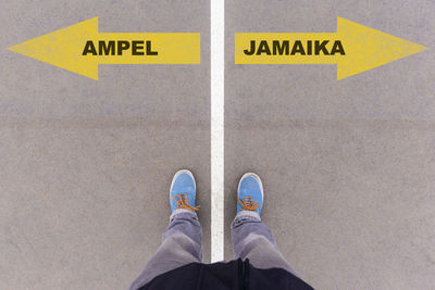 Low section of man standing on arrow sign