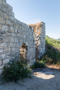 Old stone wall by building against clear sky