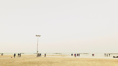 People on beach against clear sky