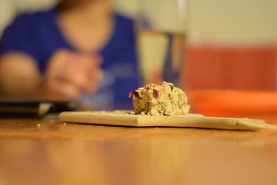 Slice of cake on cutting board at table against person