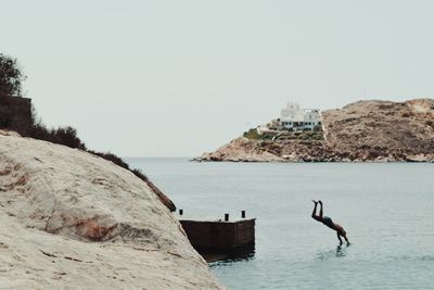 Man jumping in sea against clear sky