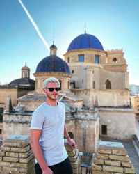 Man standing outside a temple with a beautiful sky