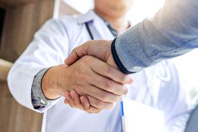 Midsection of doctor and patient shaking hands