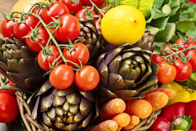 Artichokes and red cherry tomatoes in a wicker basket