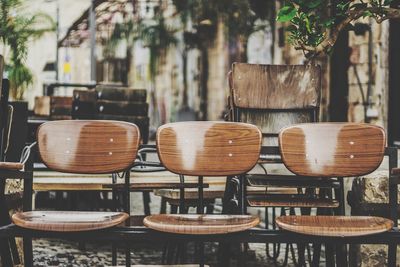 Empty wooden chairs arranged on sidewalk cafe