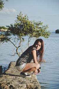 Woman crouching at lakeshore