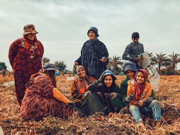 Portrait of people sitting on land against sky