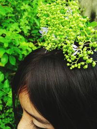 High section of woman by green buds on plant