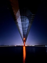 Illuminated bridge over river against sky at night