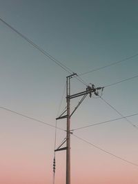 Low angle view of electricity pylon against clear sky