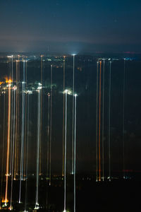 Light trails of illuminated city against sky at night
